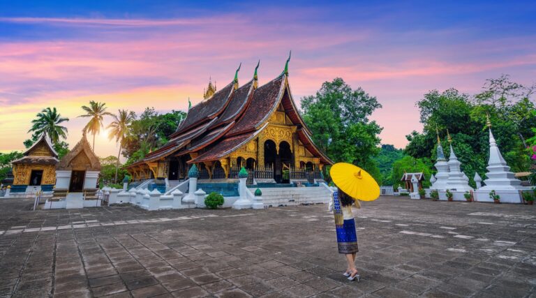 Woman with umbrella at Luang Prabang temple, Laos